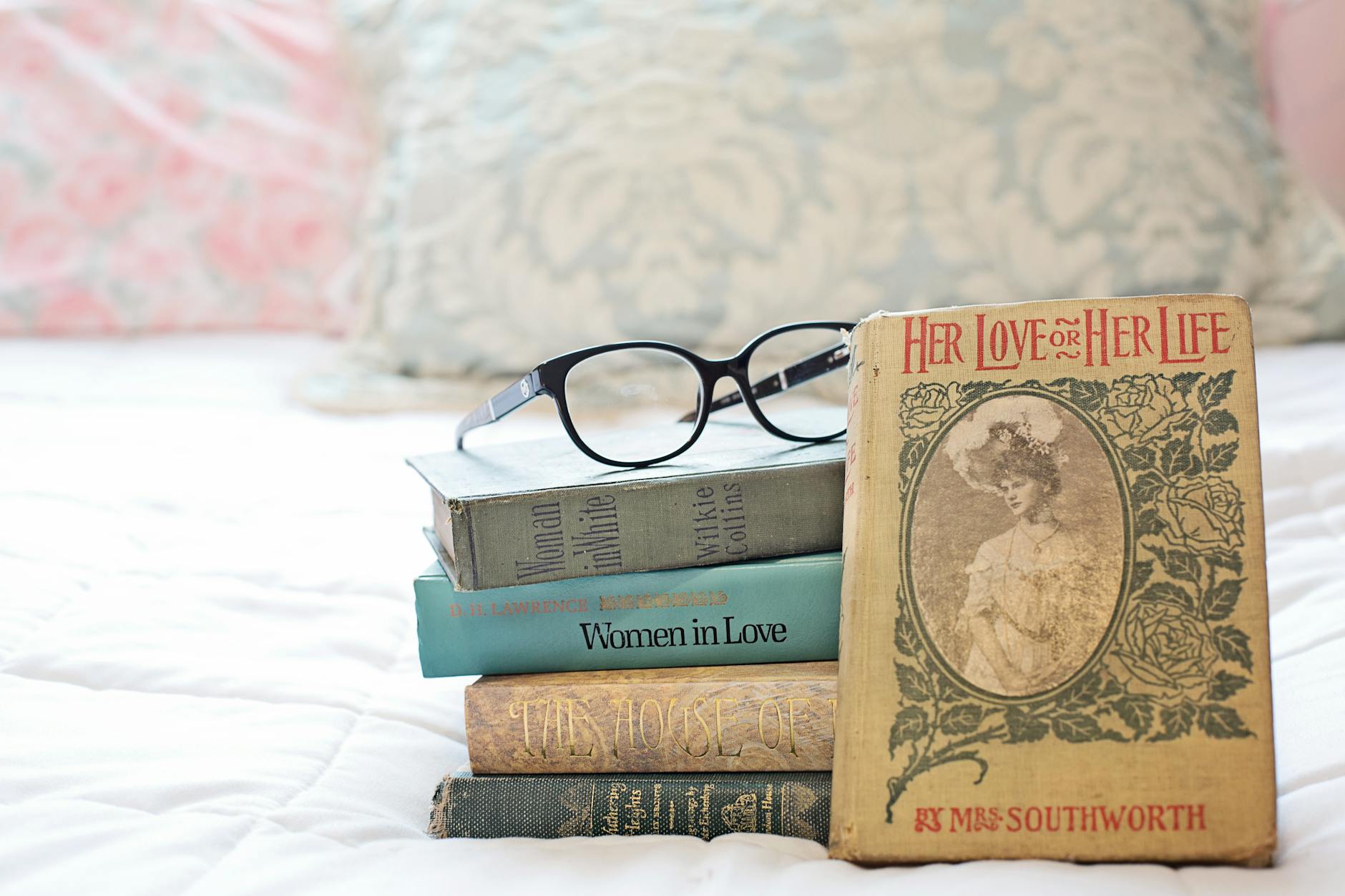 a stack of vintage books on the bed